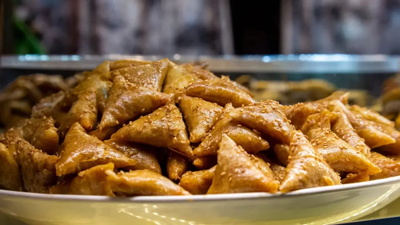 Un plateau rempli de délicieux triangles dorés, un dessert marocain traditionnel, parsemé de graines de sésame.
