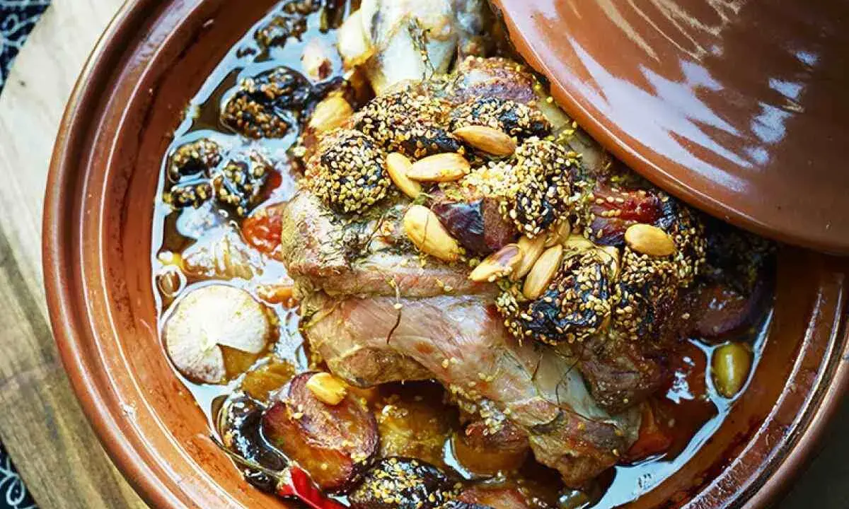 Un plat de tajine agneau aux pruneaux, amandes et sésame, mijotant dans sa sauce parfumée.