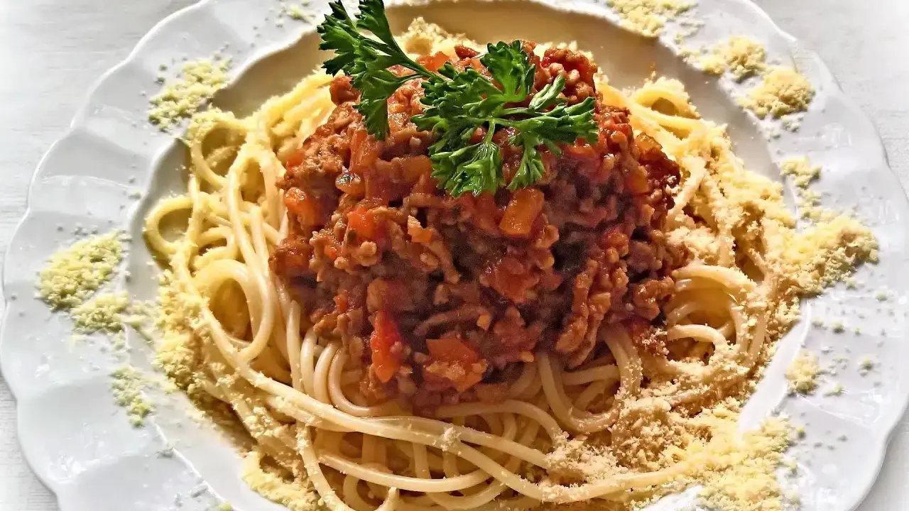 Une assiette de spaghetti bolognaise italienne, garnie de persil frais et de parmesan râpé. Un délice pour les amateurs de cuisine italienne.