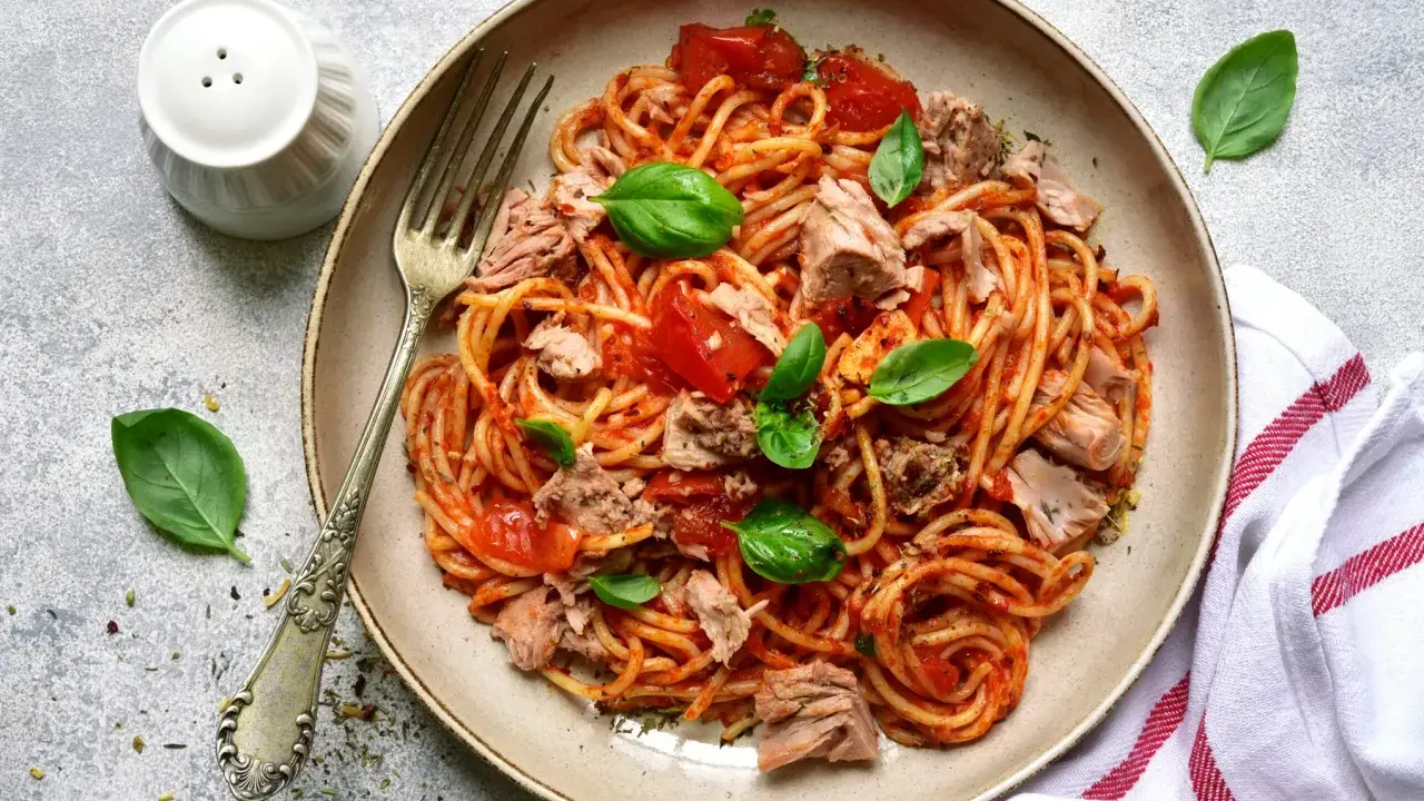 Assiette de pâtes au thon, sauce tomate et basilic frais. Un plat simple et savoureux prêt à être dégusté.