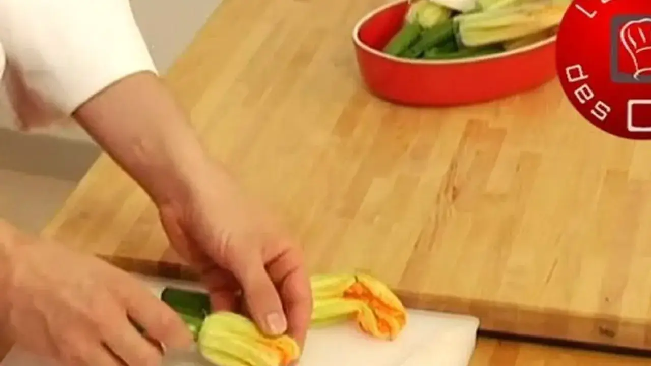 Préparation d'une fleur de courgette recette. Des mains préparent des fleurs de courgette sur une planche à découper.