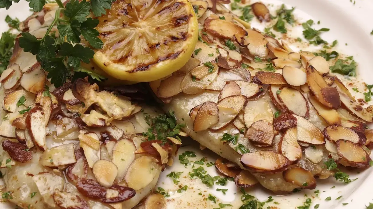Délicieuse truite aux amandes au four, garnie d'une tranche de citron grillé et de persil frais.