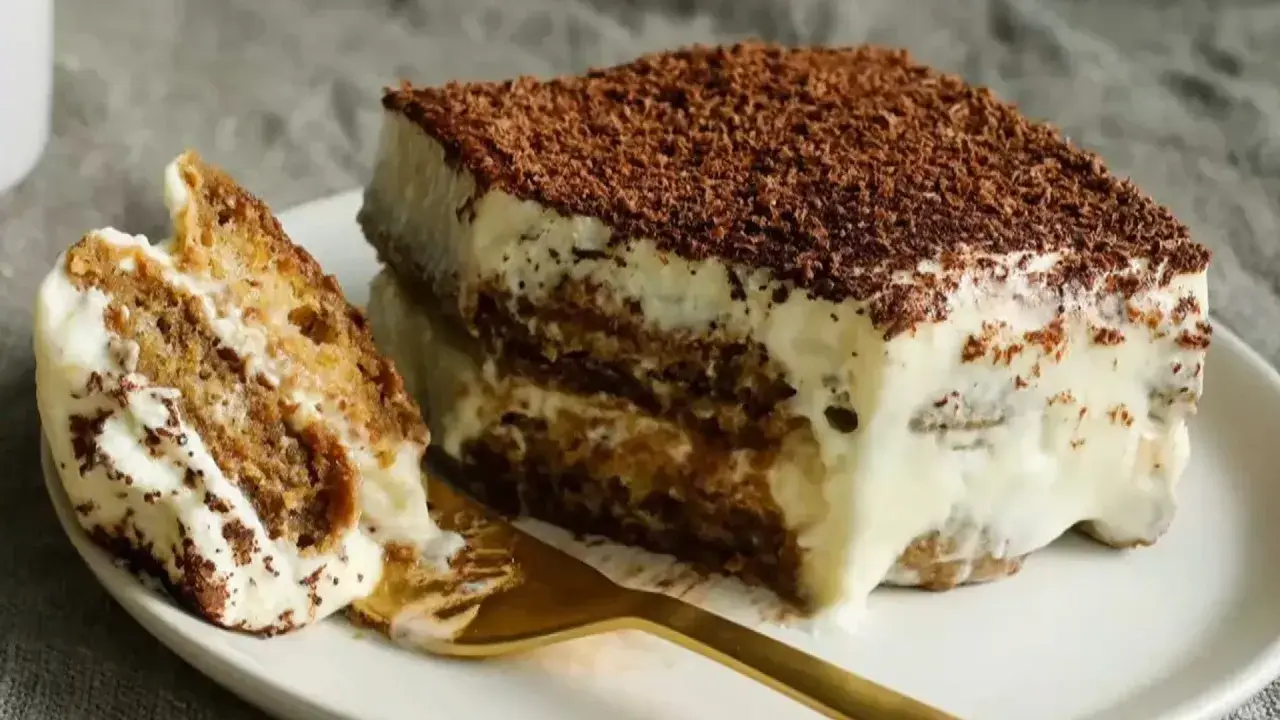 Un morceau de tiramisu, dessert aux origines italiennes, avec ses couches de biscuits imbibés et de crème onctueuse, saupoudré de cacao.