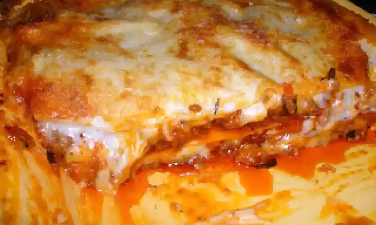 Une part généreuse de lasagne à la viande hachée, avec sa couche de fromage gratiné et sa sauce tomate débordante. Un délice réconfortant.