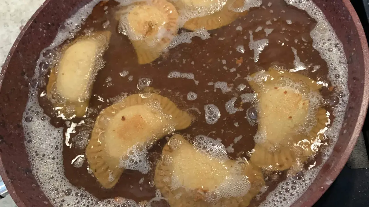 Des samboussek au fromage dorent dans l'huile chaude, formant des bulles joyeuses.