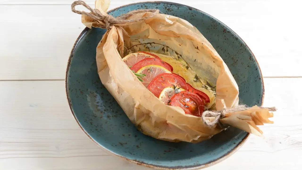 Poisson cuit en papillote avec tomates et citron, une recette bar simple et savoureuse.