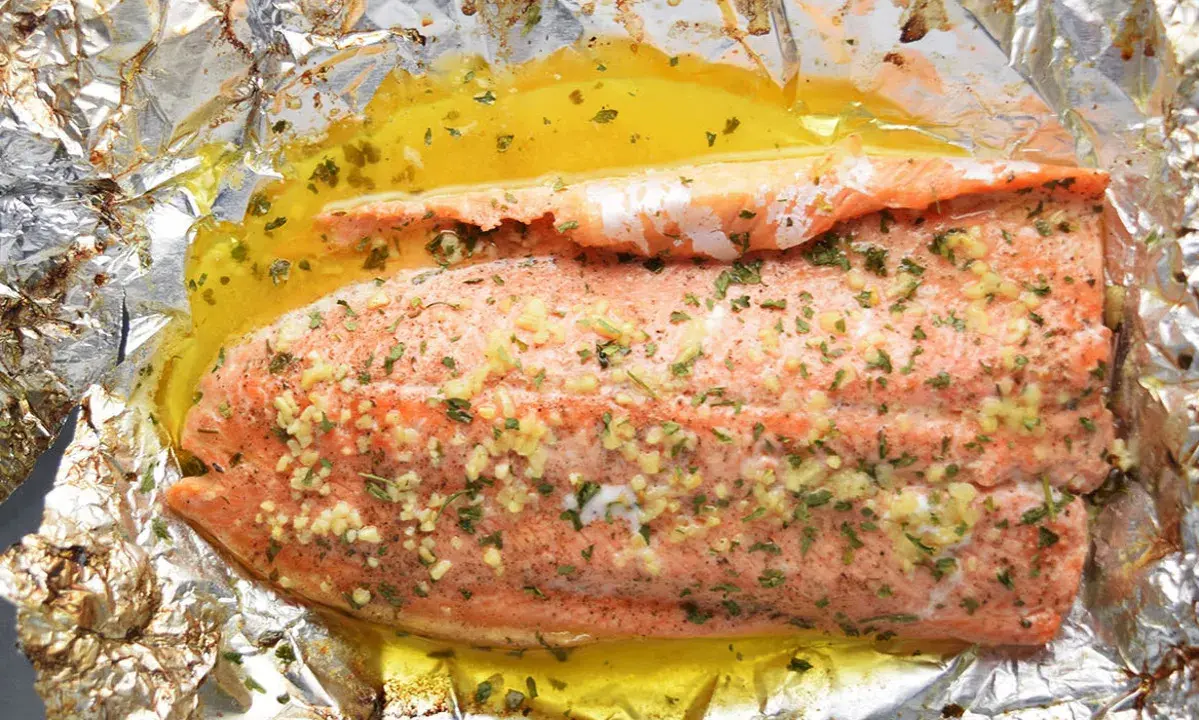 Filet de truite cuit en papillote, assaisonné d'ail et d'herbes, baignant dans un jus doré. Une recette simple et savoureuse.