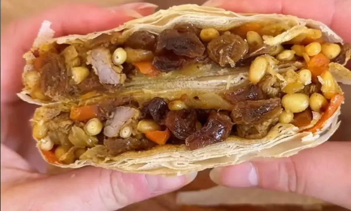 Une délicieuse pastilla agneau, coupée en deux, révèle sa garniture généreuse de viande, raisins secs, pignons et carottes.
