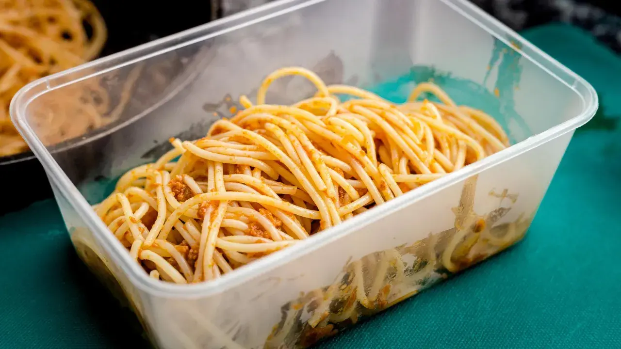 Boîte transparente remplie de spaghettis à la sauce bolognaise, idéale pour la conservation des pâtes cuites.