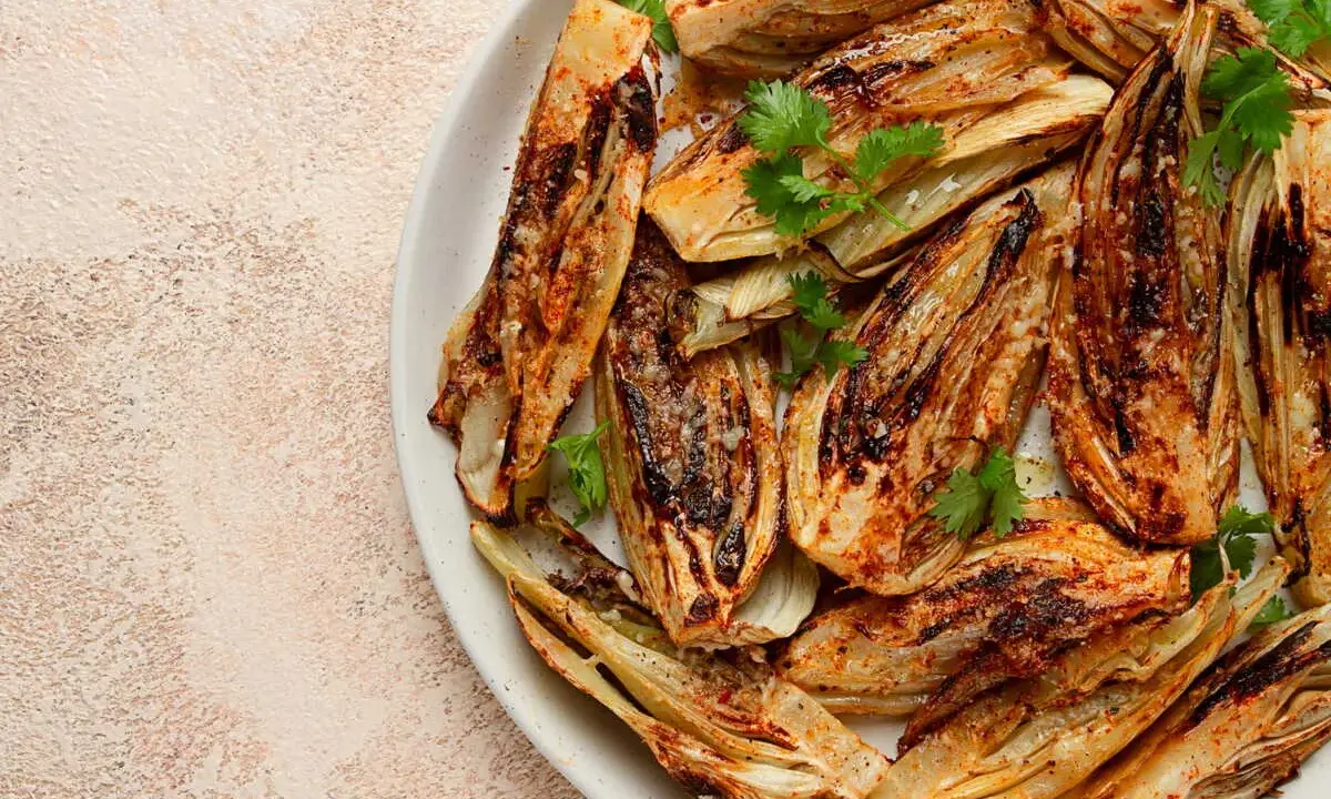 Fennouil rôti, coupé en quartiers, assaisonné et garni de coriandre fraîche. Une belle façon de cuisiner le fenouil pour un plat savoureux.