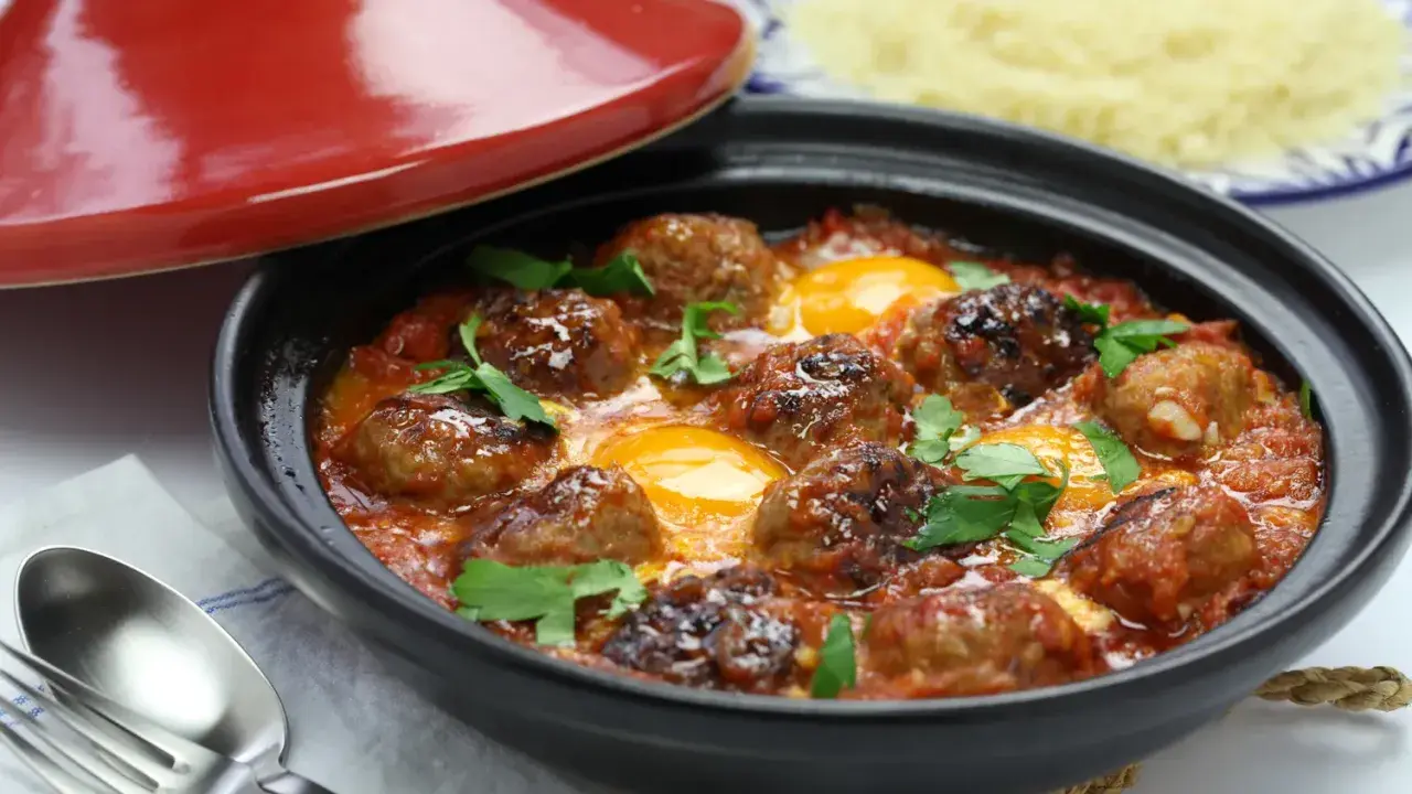 Un savoureux tajine kefta avec des boulettes de viande et des œufs pochés dans une sauce tomate épicée, garni de persil frais.