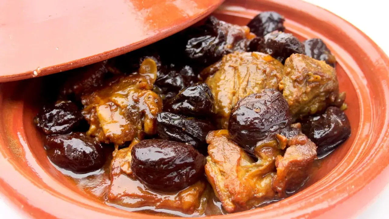 Un plat de tajine aux pruneaux, avec des morceaux de viande mijotés dans une sauce onctueuse et des pruneaux moelleux.