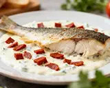Dos de cabillaud nacré, sauce crémeuse, dés de chorizo et herbes sur une assiette blanche.