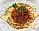 Une assiette de spaghetti bolognaise italienne, garnie de persil frais et de parmesan râpé. Un délice pour les amateurs de cuisine italienne.