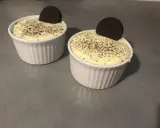 Deux ramequins de tiramisu Oreo, saupoudrés de miettes de biscuit et ornés d'un Oreo entier.