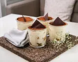 Quatre verrines de tiramisu, garnies de cacao et d'une feuille de chocolat. Une serviette grise et des petites fleurs blanches décorent le plateau en liège. Pourquoi mon tiramisu est liquide ?