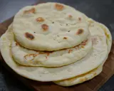 Pile de pains arabes moelleux, légèrement dorés par la cuisson, sur une planche en bois. Parfait pour accompagner un repas.