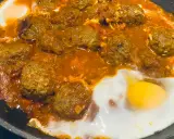 Un plat de tajine kefta oeuf mijote dans une sauce tomate épicée, avec des œufs pochés.