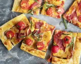 Délicieuse recette salée avec pâte filo : tartes fines garnies de tomates cerises, fromage fondant et fines tranches de charcuterie, parsemées d'herbes fraîches.
