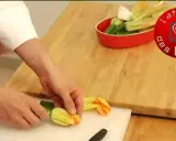 Préparation d'une fleur de courgette recette. Des mains préparent des fleurs de courgette sur une planche à découper.