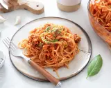 Une assiette de spaghetti à la bolognaise, plat réconfortant de one pot pasta, garnie d'herbes fraîches.