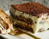 Un morceau de tiramisu, dessert aux origines italiennes, avec ses couches de biscuits imbibés et de crème onctueuse, saupoudré de cacao.