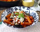 Pâtes rigatoni généreusement garnies de sauce tomate, d'aubergines grillées et de fromage râpé, le tout surmonté d'une feuille de basilic frais. Un plat de pâtes aubergines appétissant.