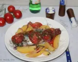 Maquereau au vin blanc, pommes de terre, tomates et oignons sur une assiette blanche.