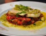 Délicieux dos de cabillaud à la poêle, servi sur un lit de légumes méditerranéens et arrosé d'une sauce verte.