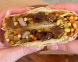 Une délicieuse pastilla agneau, coupée en deux, révèle sa garniture généreuse de viande, raisins secs, pignons et carottes.