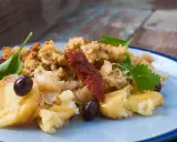 Morue à bras, un plat réconfortant avec des flocons de poisson, des olives noires, des tomates séchées et une touche de persil frais.