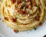 Un plat de pâtes carbonara végétariennes, garni de chapelure croustillante et de persil frais.