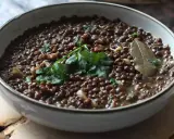 Un plat de cuisson lentilles vertes, garni de persil frais et d'une feuille de laurier. Un délice simple et réconfortant.