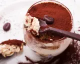 Un déliceux tiramisu cacao, saupoudré de cacao, avec une cuillère pleine de crème onctueuse et un grain de café.