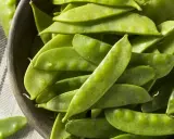 Un bol en bois rempli de pois gourmands frais, prêts pour la cuisson.