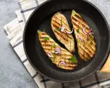 Aubergines grillées dans une poêle, garnies d'oignons rouges et de persil. Une délicieuse recette aubergine prête à être dégustée.