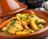 Un plat de tajine recette traditionnelle, avec du poulet, des carottes, des olives et des abricots, garni de persil frais.