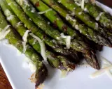Un plat d'asperges au four, tendres et légèrement grillées, parsemées de copeaux de parmesan. Un délice simple et savoureux.