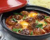 Un savoureux tajine kefta avec des boulettes de viande et des œufs pochés dans une sauce tomate épicée, garni de persil frais.