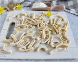 Des pâtes fraîches, prêtes à être cuites. Un aperçu de comment faire des pâtes maison, avec un rouleau à pâtes et de la farine.