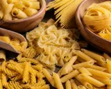 Assortiment de pâtes italiennes : fusilli, farfalle, penne, rigatoni et spaghetti, évoquant la qualité de la farine pour pâtes italiennes.