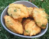 Un bol rempli de beignets de morue portugais dorés, parsemés d'herbes vertes, sur un fond d'herbe.