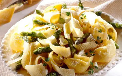 Pâtes aux asperges, garnies de copeaux de parmesan et de persil frais. Un plat printanier savoureux.