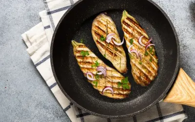 Aubergines grillées dans une poêle, garnies d'oignons rouges et de persil. Une délicieuse recette aubergine prête à être dégustée.