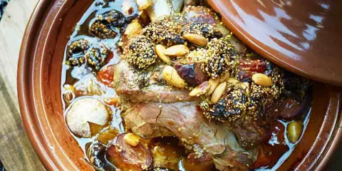 Un plat de tajine agneau aux pruneaux, amandes et sésame, mijotant dans sa sauce parfumée.