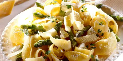 Pâtes aux asperges, garnies de copeaux de parmesan et de persil frais. Un plat printanier savoureux.