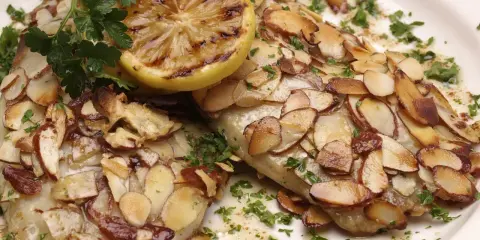 Délicieuse truite aux amandes au four, garnie d'une tranche de citron grillé et de persil frais.