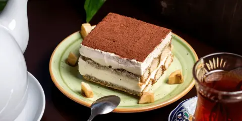 Un tiramisu onctueux, saupoudré de cacao, servi avec des morceaux de fruits. Une idée pour par quoi remplacer le café dans le tiramisu ?