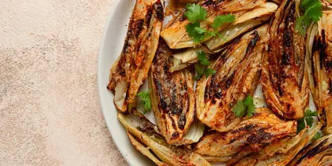 Fennouil rôti, coupé en quartiers, assaisonné et garni de coriandre fraîche. Une belle façon de cuisiner le fenouil pour un plat savoureux.