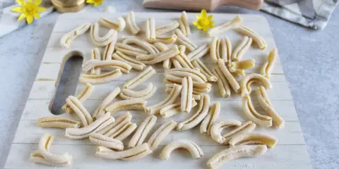 Des pâtes fraîches, prêtes à être cuites. Un aperçu de comment faire des pâtes maison, avec un rouleau à pâtes et de la farine.